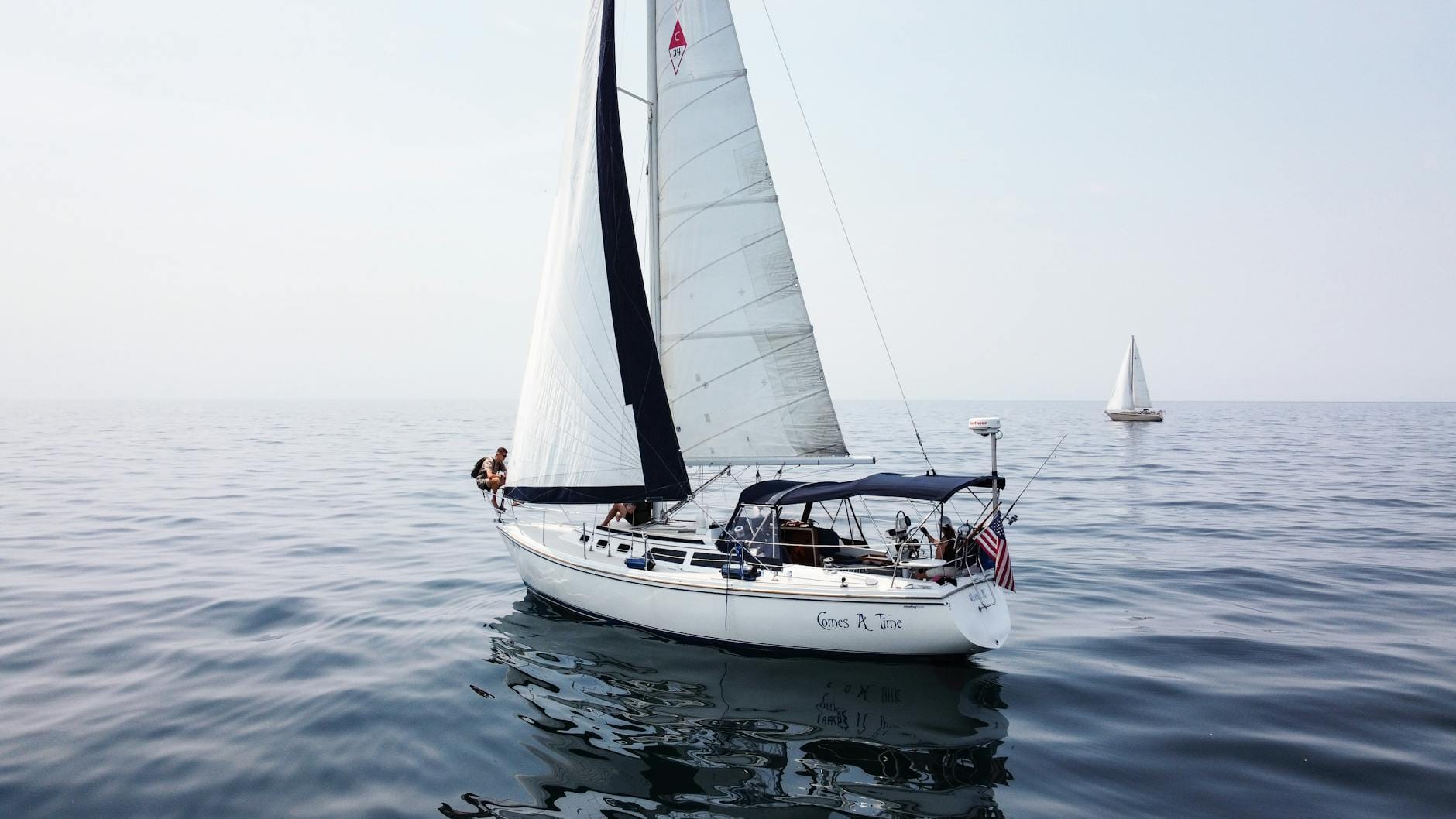 Dwa jachty żaglowe mijają się na spokojnej wodzie jeziora