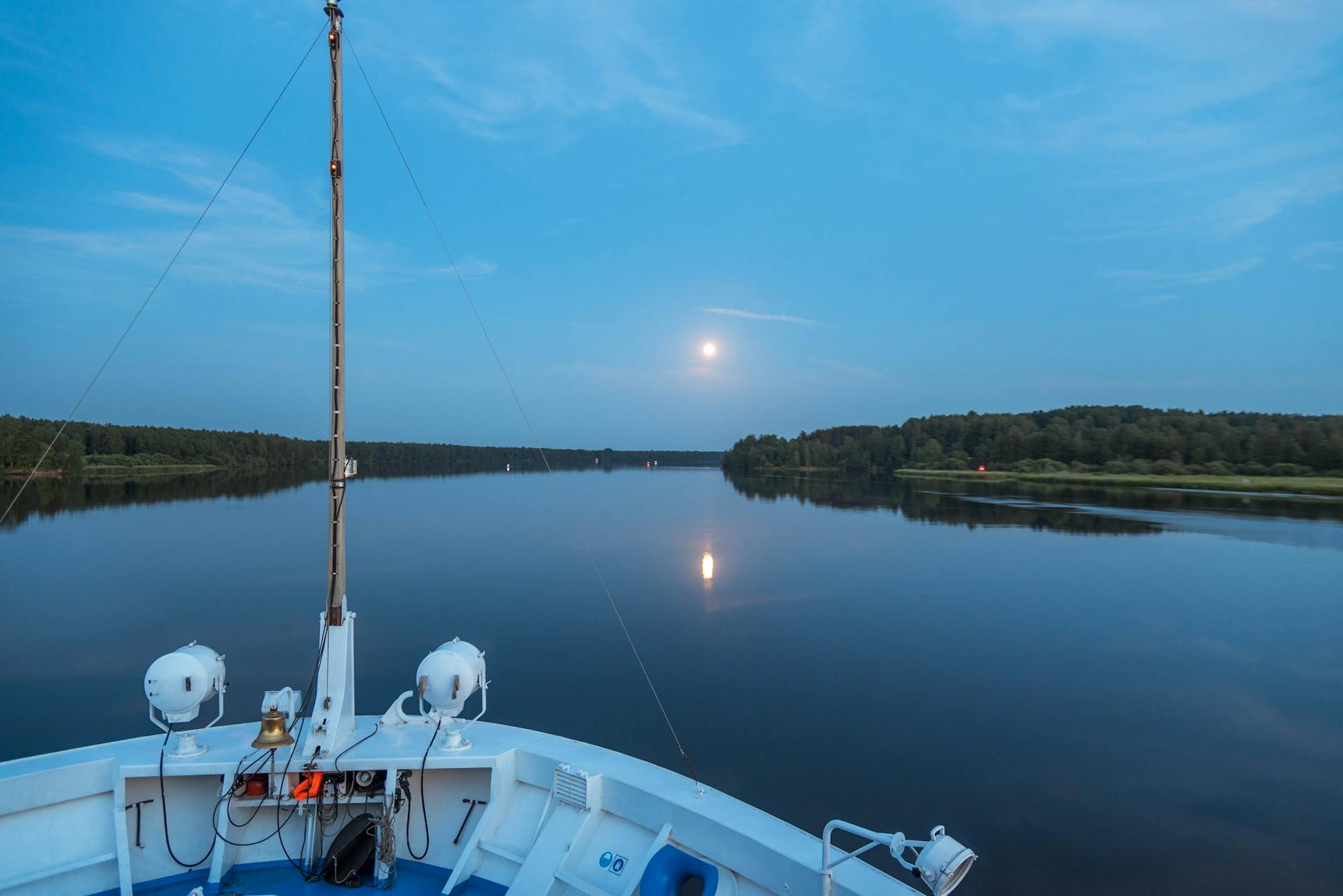 Jacht płynie nocą po spokojnym jeziorze w blasku pełni księżyca