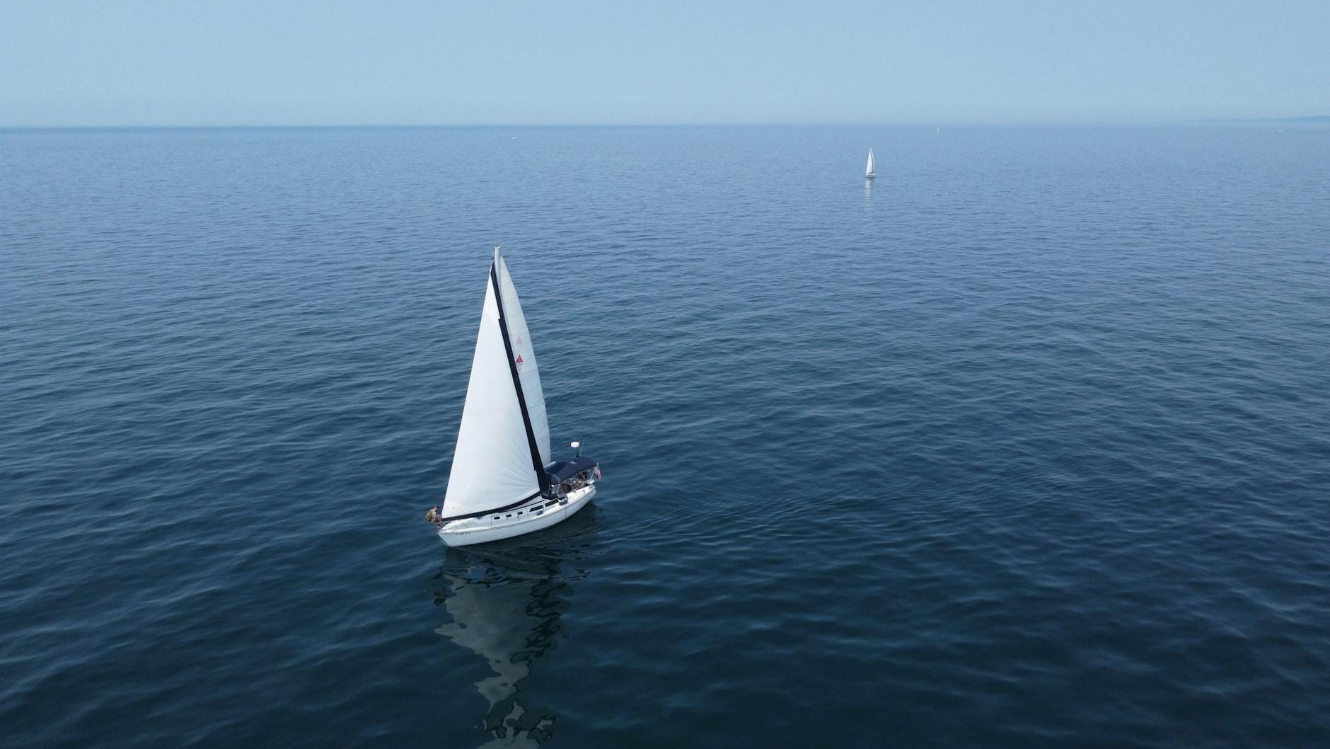 Jachty żeglujące po spokojnej tafli jeziora w słoneczny dzień