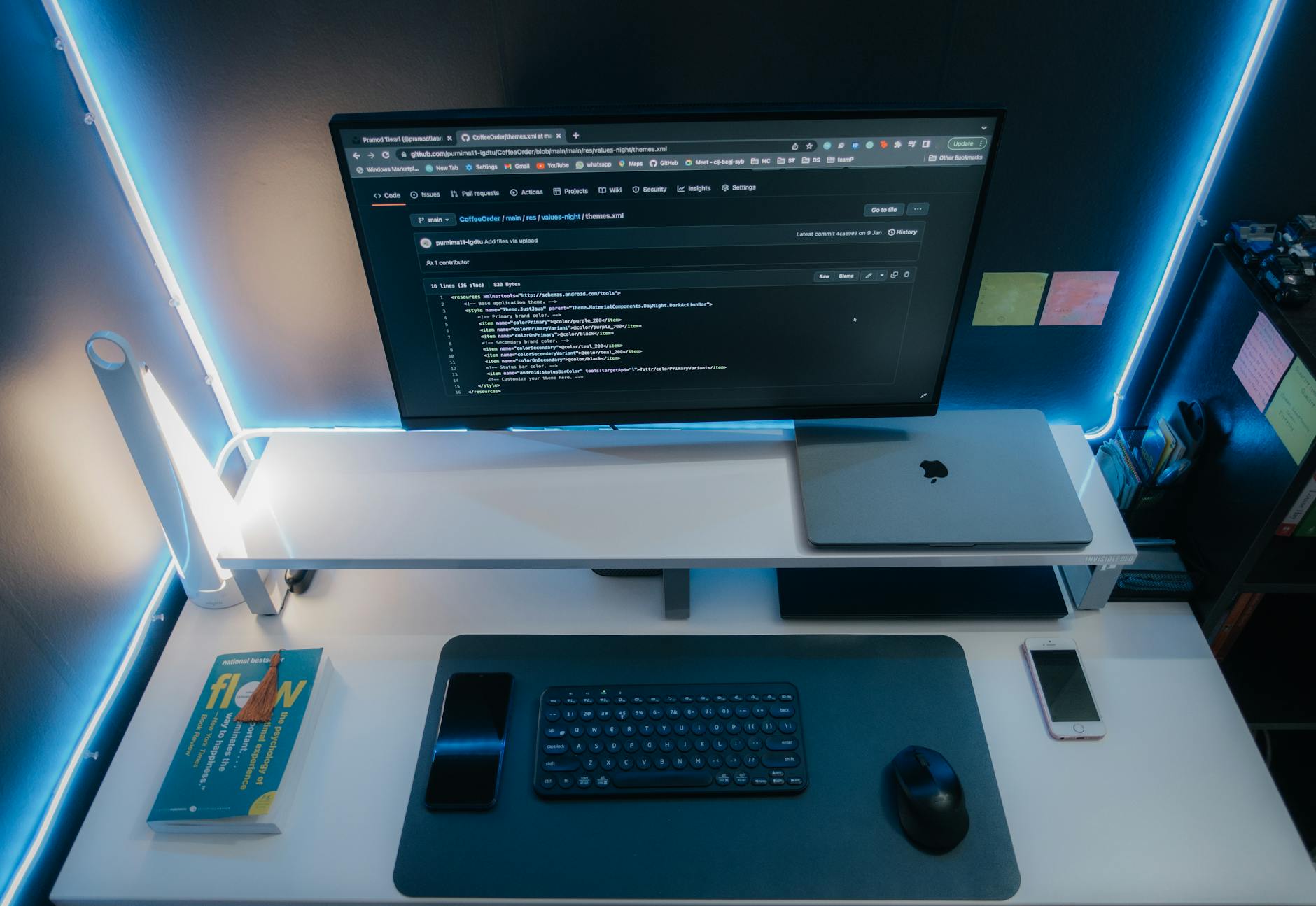 Minimalistyczne biurko z komputerem i gadżetami w neonowym oświetleniu
