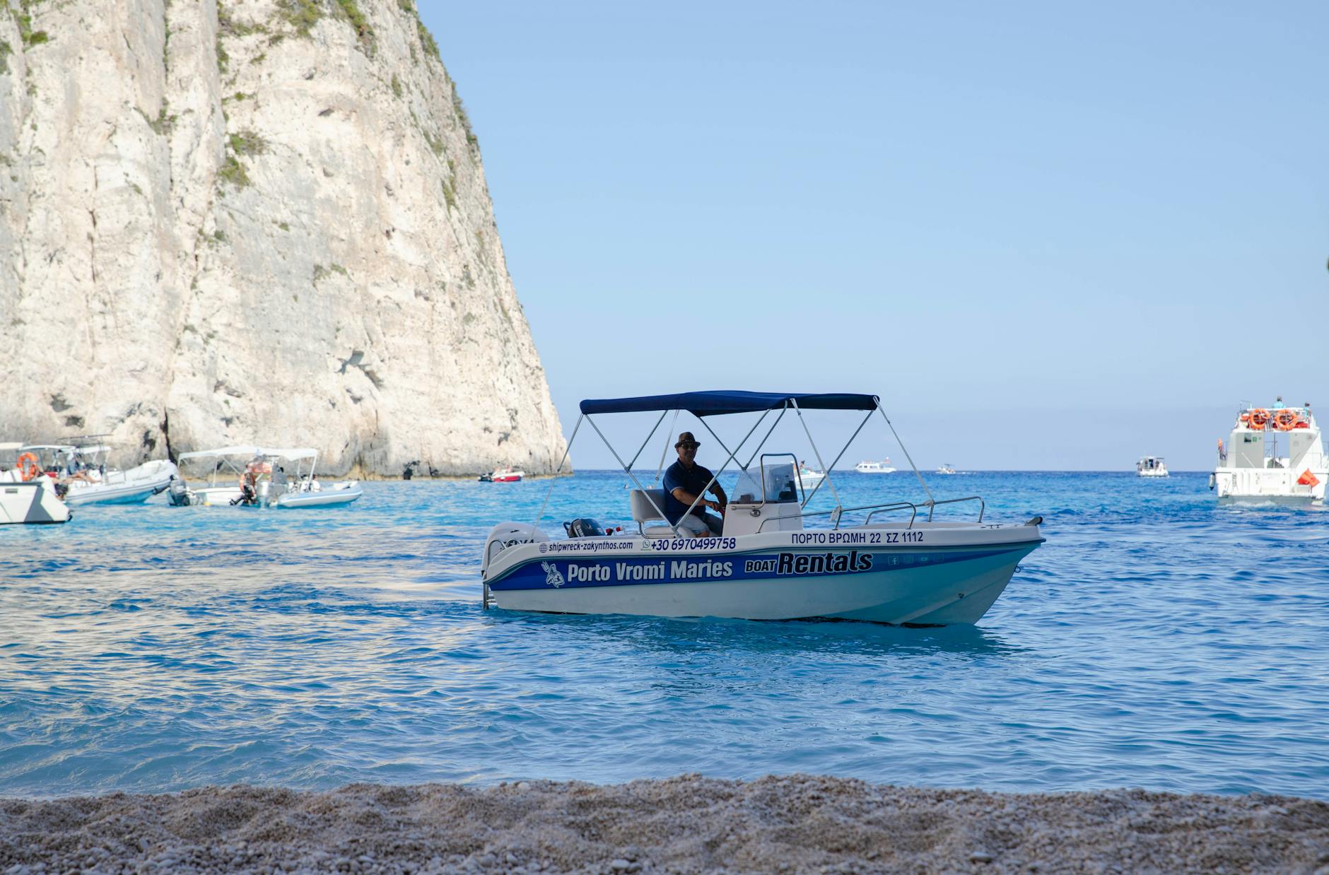 Motorówka płynie po lazurowej wodzie u skalistego wybrzeża Zakynthos