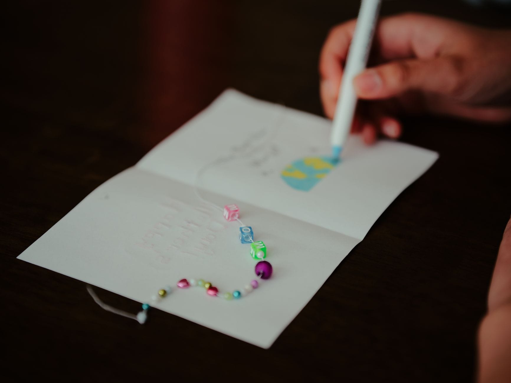 Personalizowane prezenty DIY na ślub i urodziny: pomysły krok po kroku do 50, 100 i 200 zł Dłoń ozdabia własnoręcznie robioną kartkę koralikami i długopisem